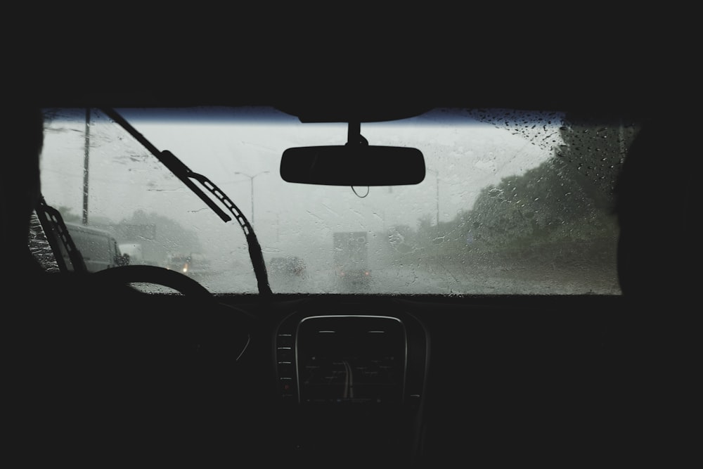 Two people driving on rainy road with wipers