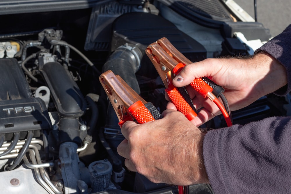 Person holding red and black jump starter tool