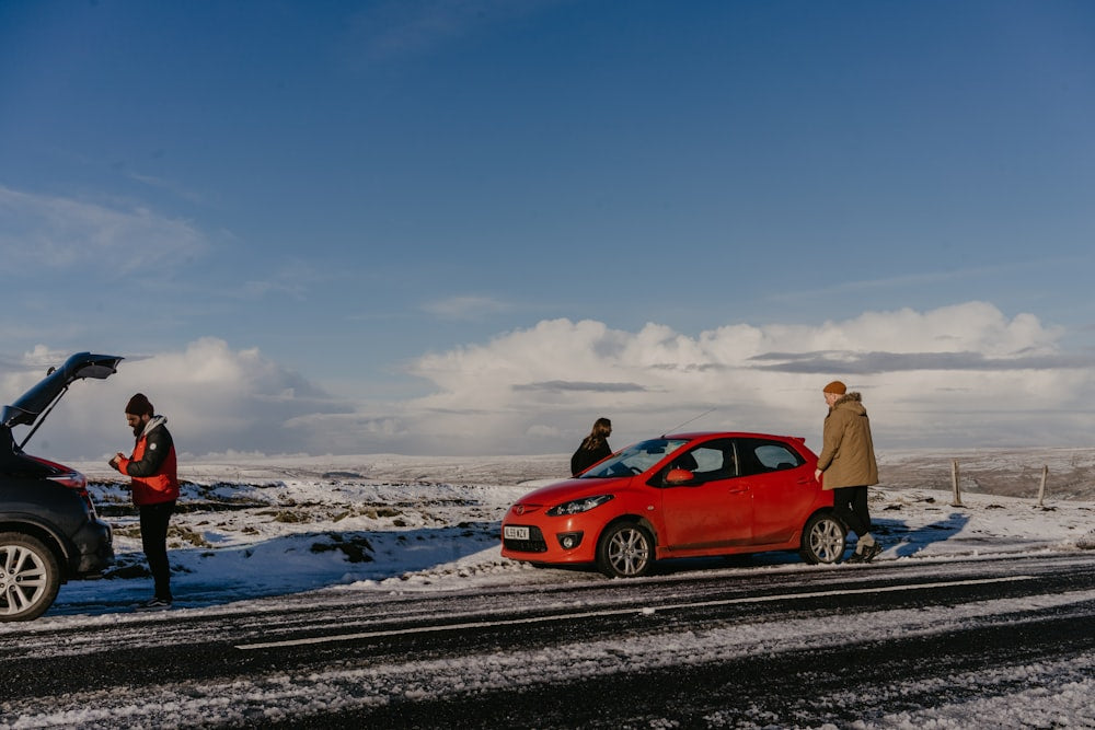 Man beside red car stranded on snowy road