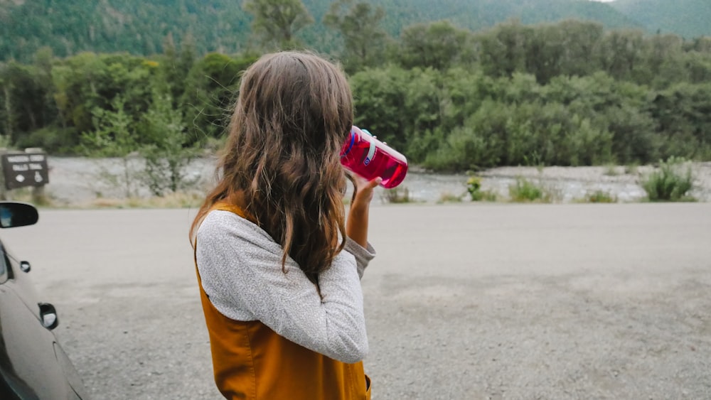 Woman with travel cup beside car