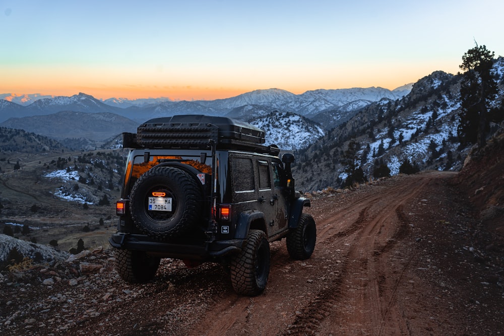 Jeep driving down a dirt road with mountains