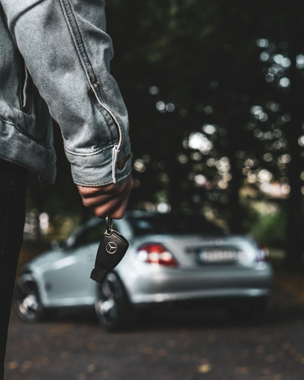 Person holding car key next to silver car