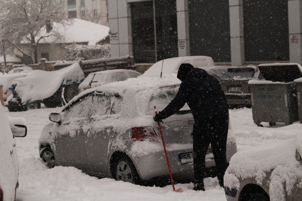 Person shoveling snow off car