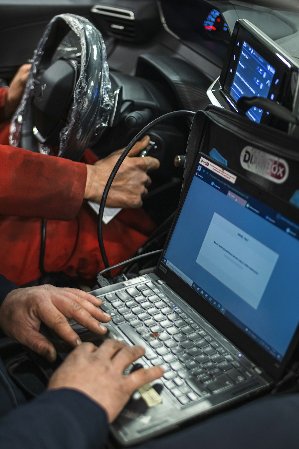 Man sitting in a car using a diagnostic laptop