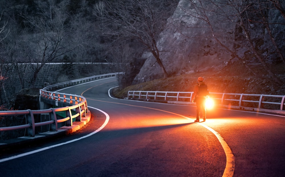 Person standing in front of car on road with flares