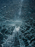 Shattered windshield glass with impact point