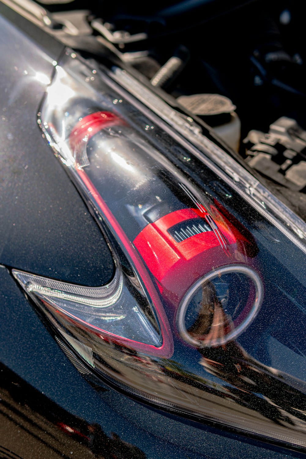 A red car vacuum cleaner on a dark car hood